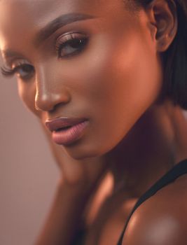 Close-up studio portrait of a young woman with a glamorous look, showcasing elegant makeup and clear skin.