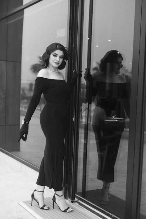 Black and White Photo of an Elegant Woman Standing by the Door 