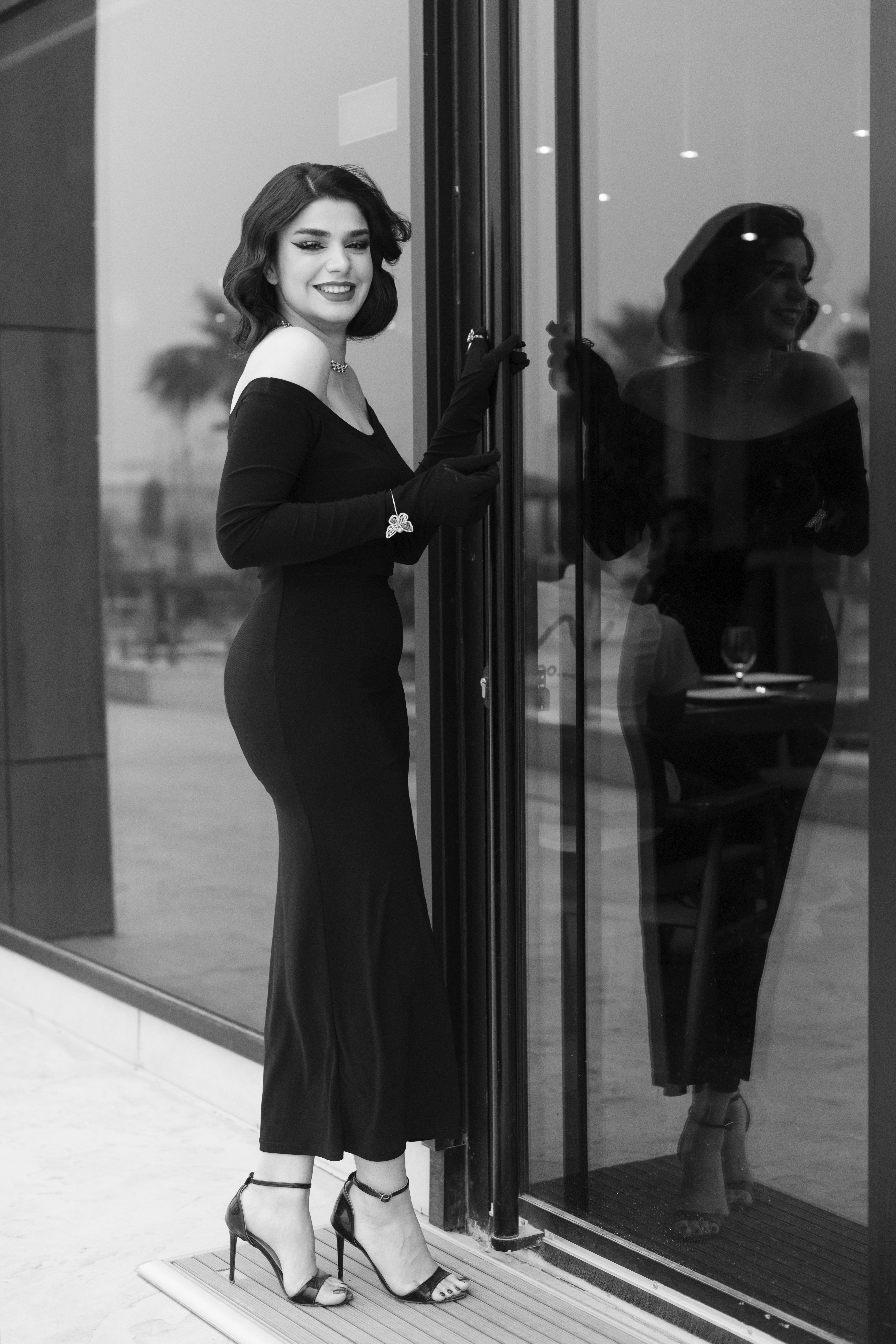 Young Elegant Woman in a Long Black Dress and High Heels Standing by the  Window and Smiling  Free Stock Photo