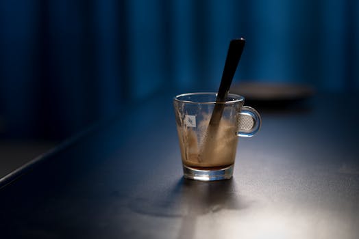 一张阴郁的照片里，空浓缩咖啡杯和勺子摆在昏暗的桌面上