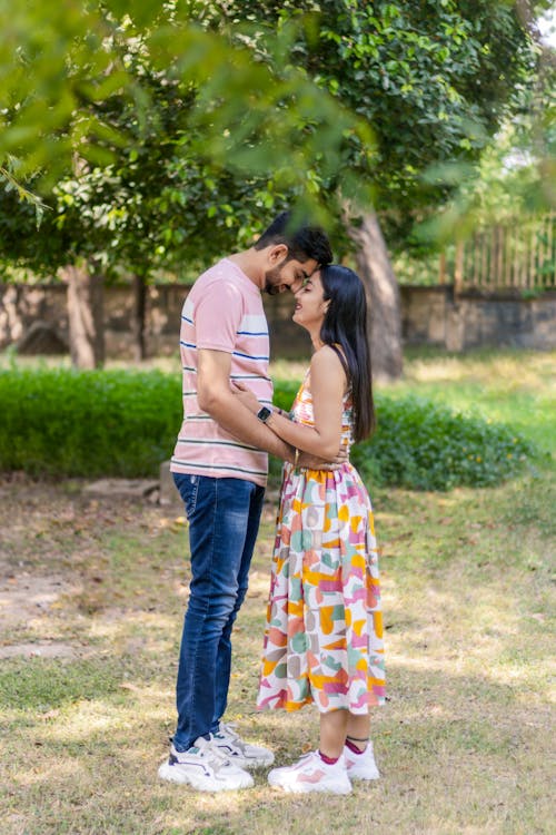 A Couple Standing Head to Head in a Park and Smiling 