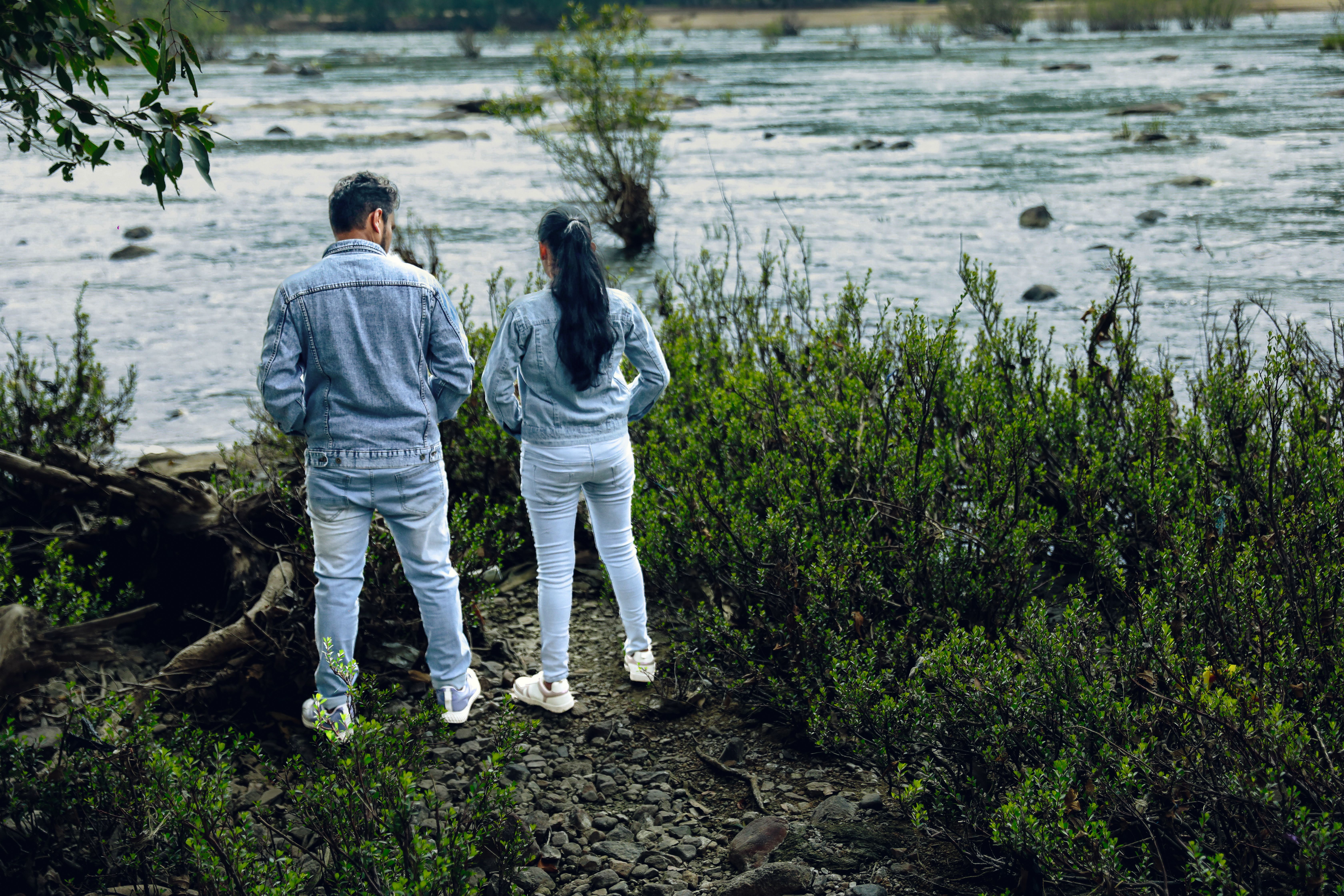 Couple Dressed in Denim Standing on a Riverbank · Free Stock Photo