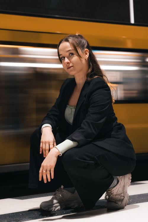 Free Candid shot of a woman posing at a Berlin train station with a train in motion. Stock Photo