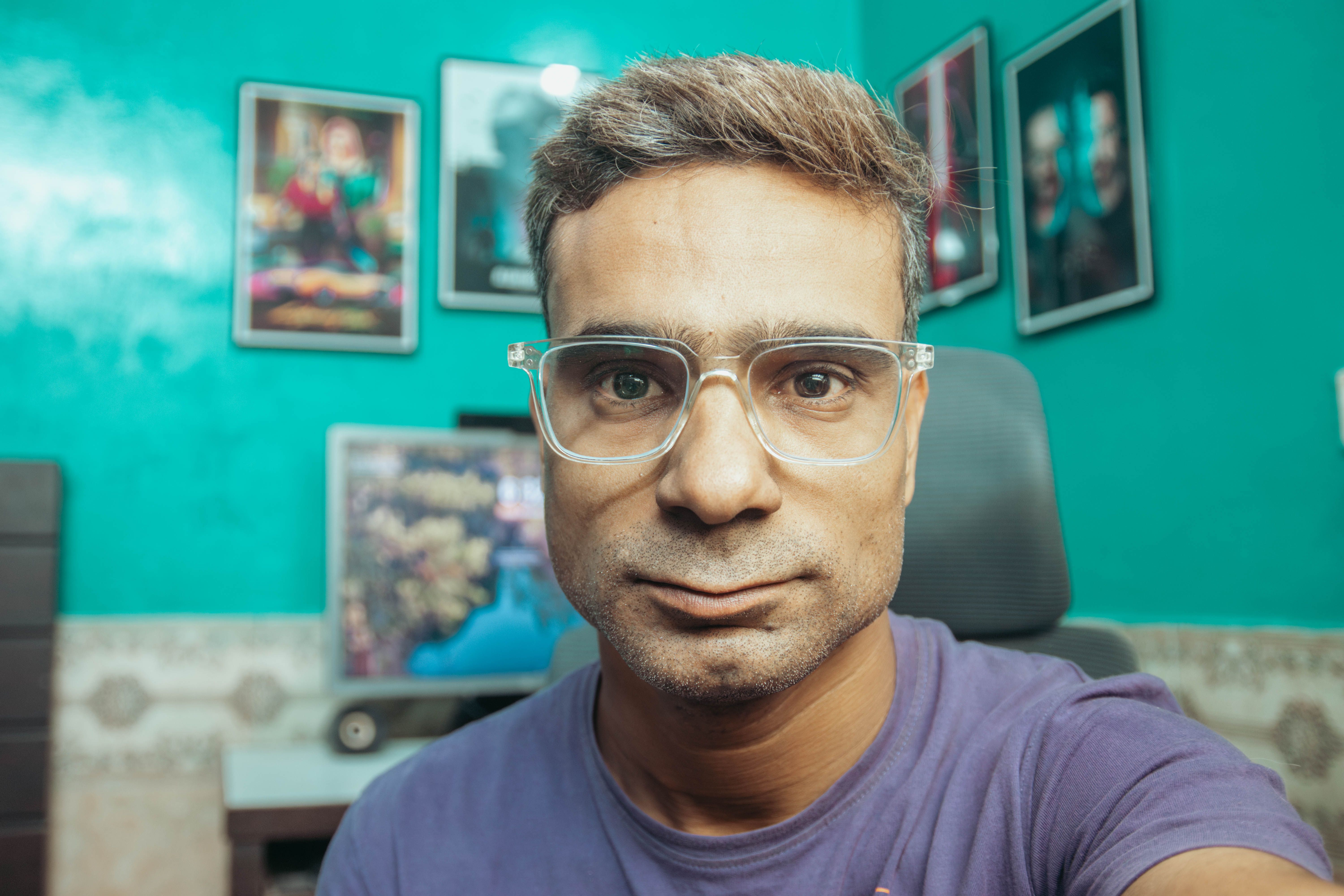 Close-up of a man with eyeglasses in a vibrant, decorated room. Interior setting.