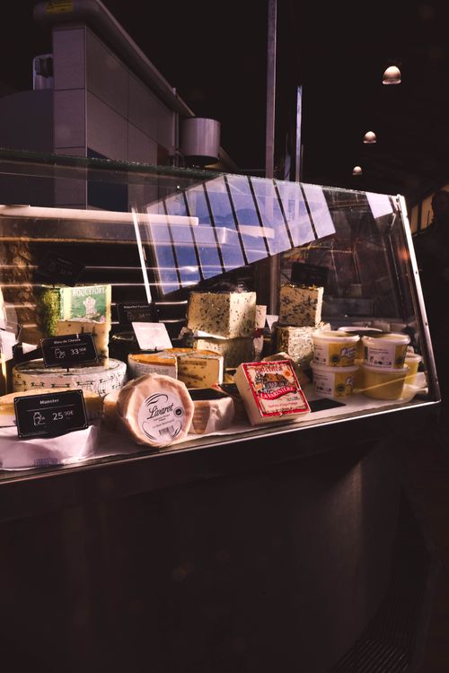 Free Assorted cheeses in a glass case at a market in Thouars, France. Stock Photo
