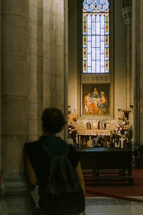 Free A woman admiring religious art in a historic church interior with stained glass windows. Stock Photo