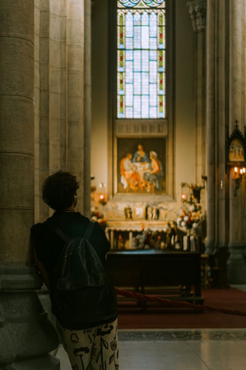 Free A person with a backpack stands in a historic church, admiring the stained glass and altar. Stock Photo