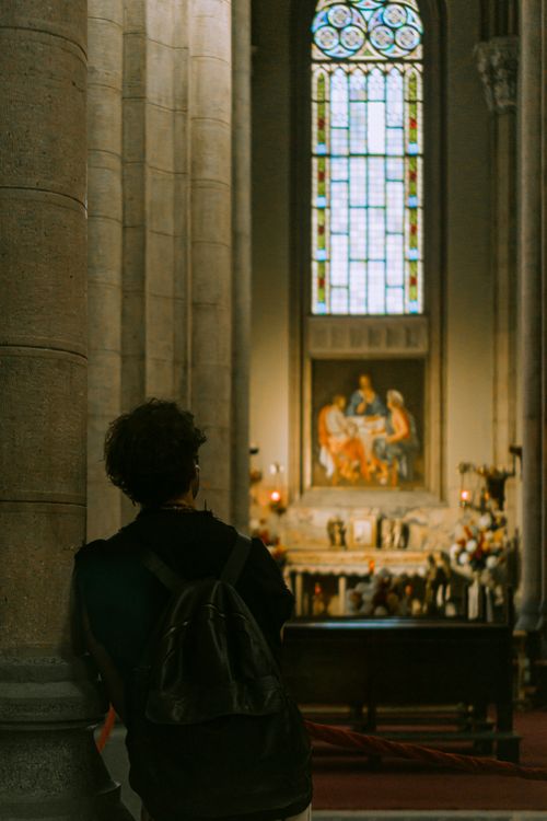 Free Back view of person in a Gothic cathedral gazing at a decorative altar with stained glass window. Stock Photo