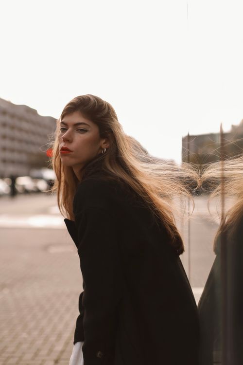 Free Fashionable woman in black coat with flowing hair in an urban Berlin backdrop. Stock Photo