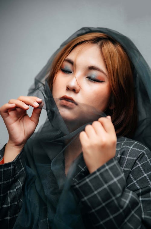 Studio Shot of a Young Woman Wearing Tulle Fabric on Her Head 