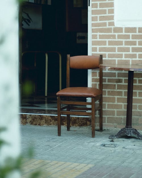 A Chair and Table Standing Outside of a Building on the Pavement 