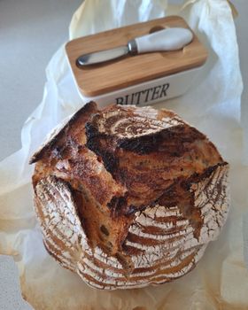 Rustic homemade sourdough bread with butter dish in kitchen setting.