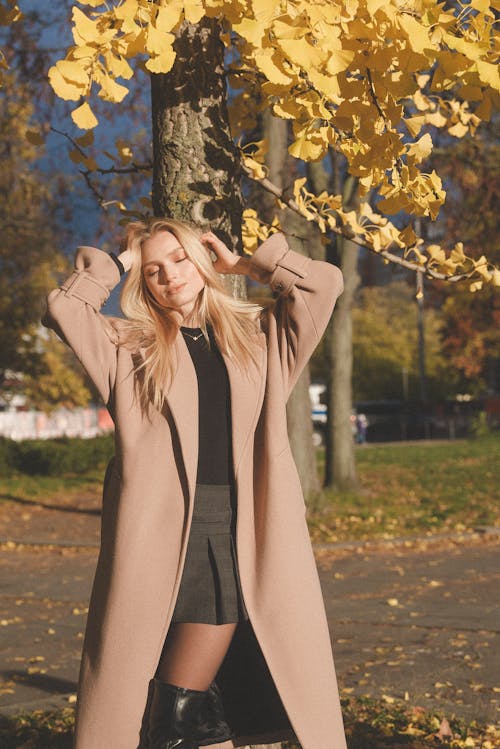 Blonde Woman with Eyes Closed Standing in Coat in Autumn