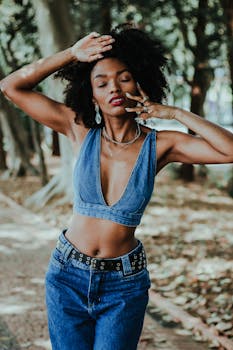 Fashionable African woman posing in denim outfit in a park setting.