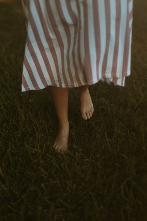 Woman Walking on Grass in Stripped Dress