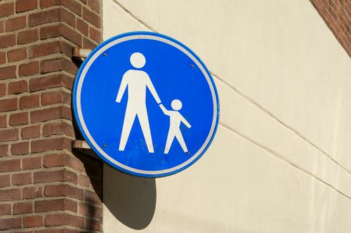 Free Blue pedestrian crossing sign mounted on a sunny urban brick wall intersection. Stock Photo
