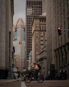 A man cycles through the streets of downtown Pittsburgh with the Highmark building in the background.