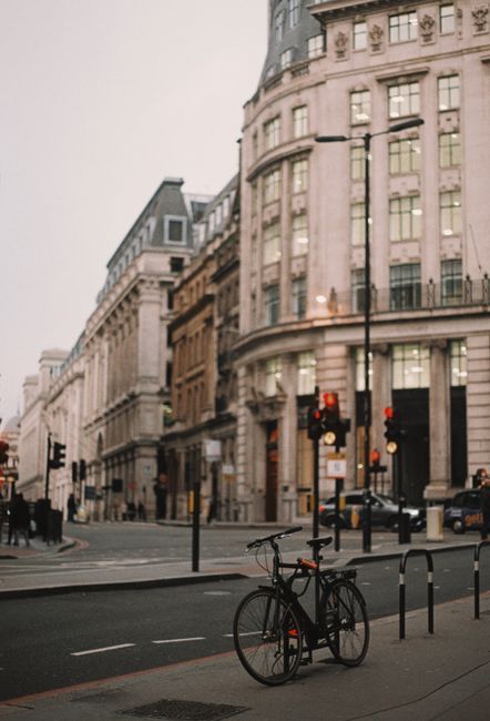 A bicycle rests on a quiet street in London surrounded by historic architecture.
