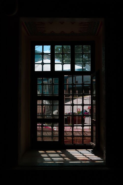Free A dimly lit interior scene showcasing an antique window with intricate shadow patterns. Stock Photo