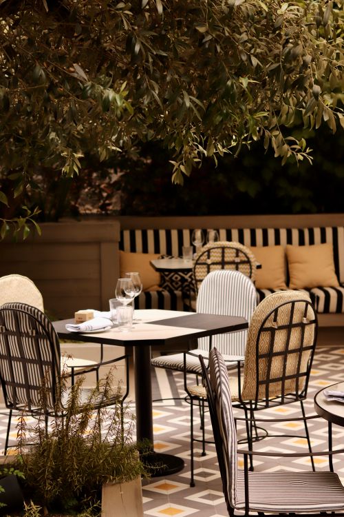 Free Elegant restaurant terrace in Barcelona with stylish furniture under shaded trees. Stock Photo