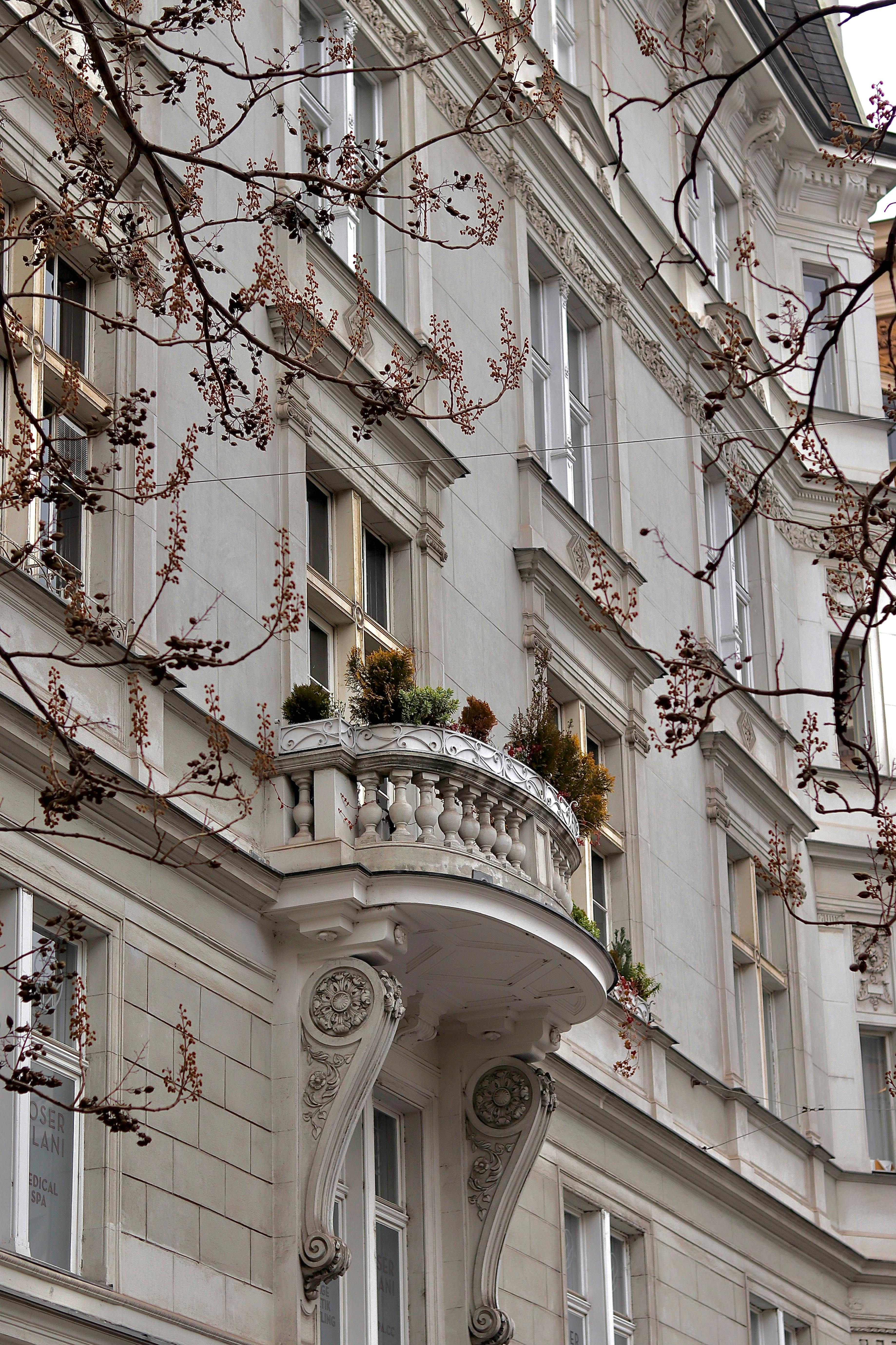 Classic Viennese building with ornate balcony and trees in view.