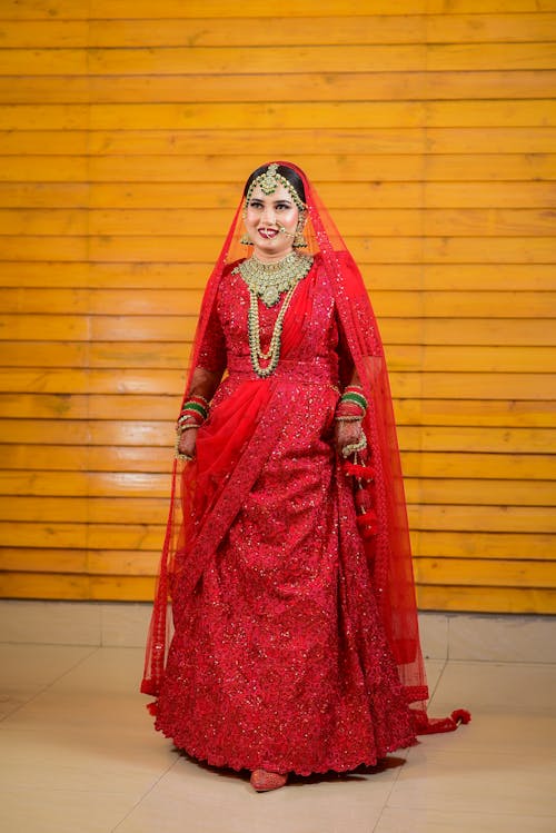 Brunette Bride in Traditional Red Dress Standing by Wooden Wall