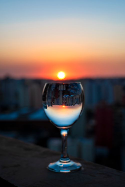 Free Stunning reflection of a cityscape sunset in a wine glass, creating a unique visual effect. Stock Photo