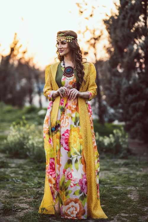 Free Woman in colorful traditional clothing standing outdoors at sunset, exuding elegance and style. Stock Photo