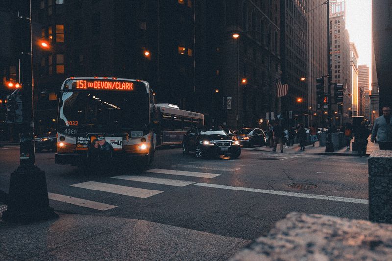 Urban scene with bus and traffic in a city setting at twilight, highlighting urban life.