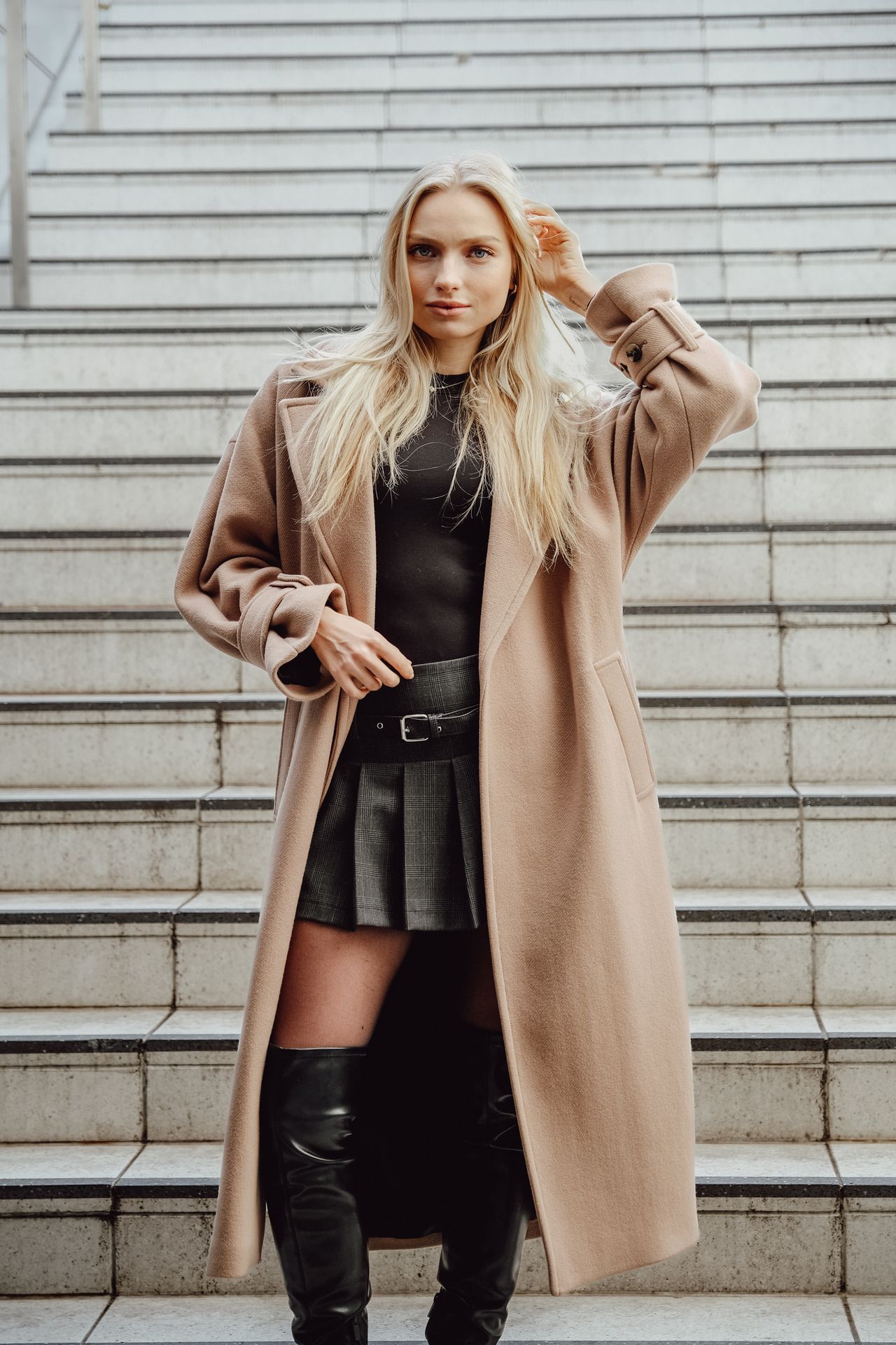 Woman in a camel wool coat and black boots on steps
