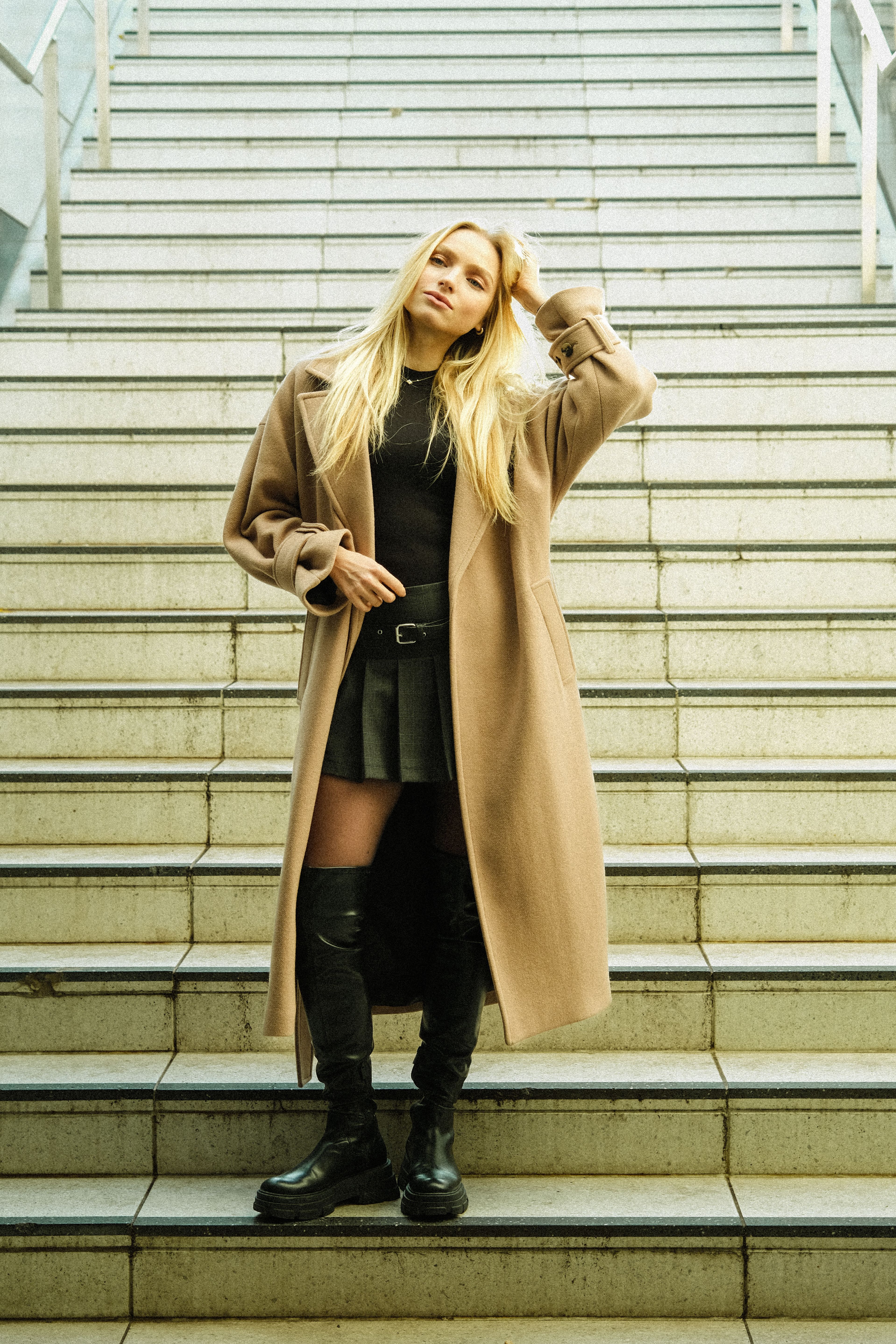 Person Posing on Steps in a Trench Coat Ruffling Hair · Free Stock Photo