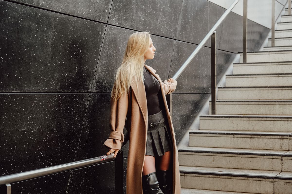 Woman in a trench coat and leather boots showing autumn street style