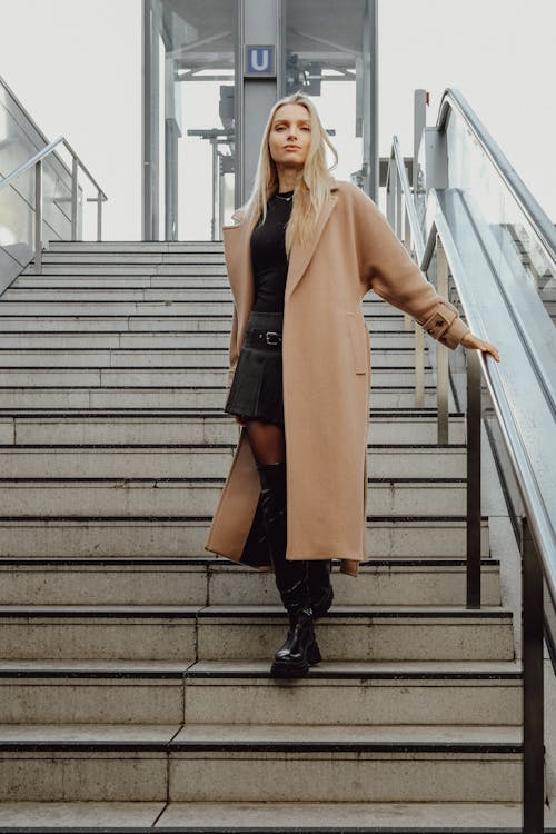 Blonde Woman in Coat Standing on Stairs
