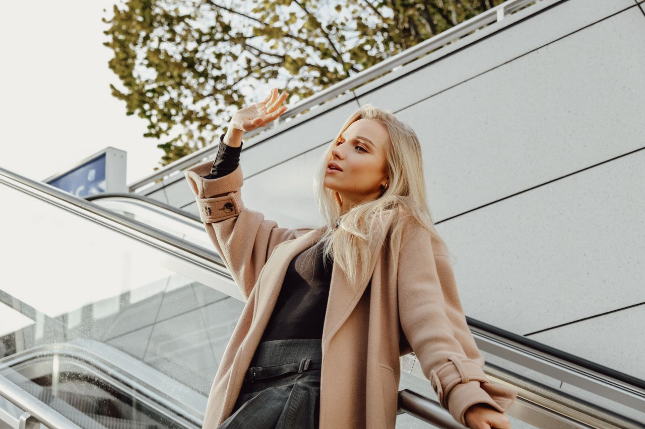 fashionable blonde woman posing on an outdoor escalator showcasing mod
