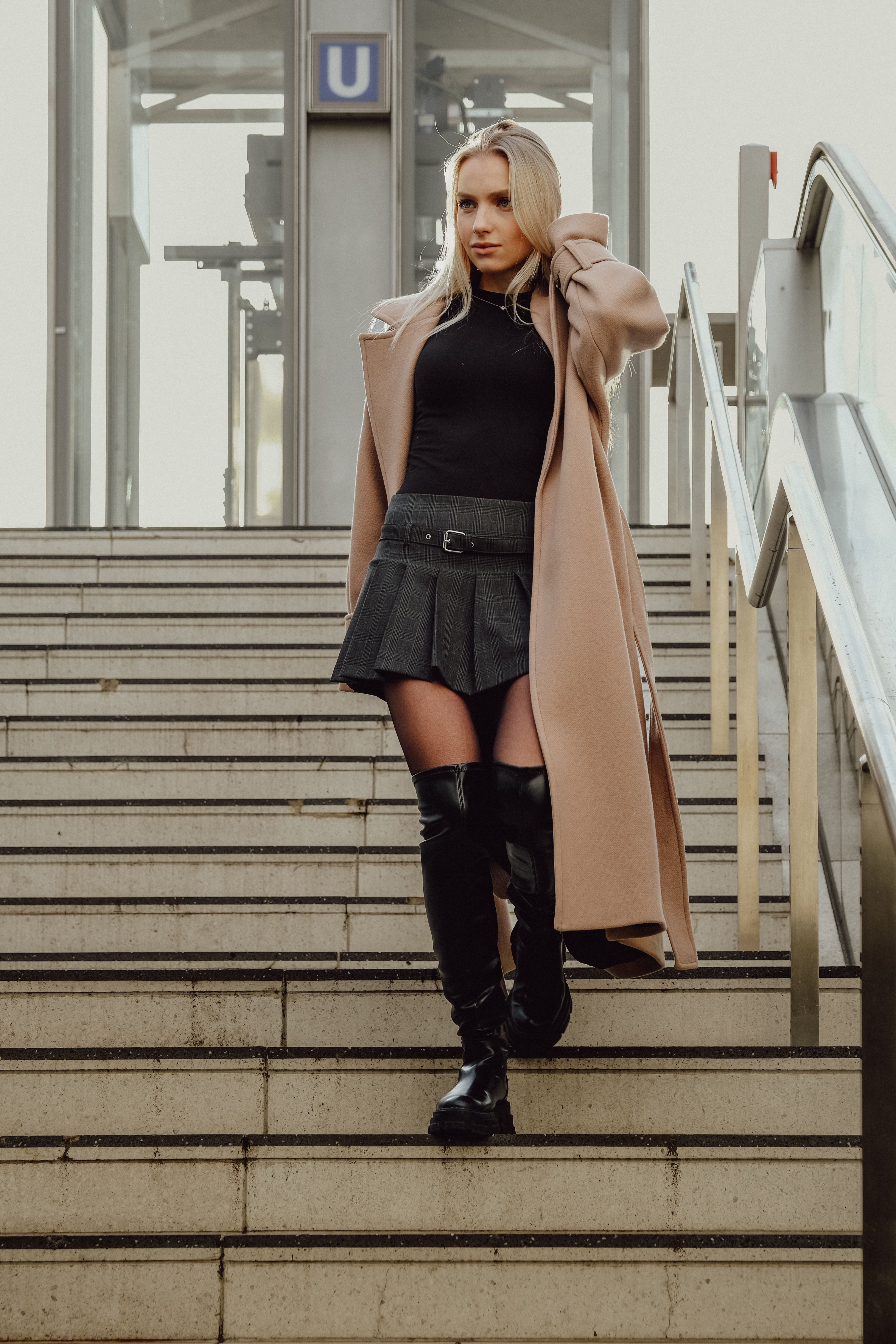 Blonde Woman in a Coat, a Skirt and Boots Walking Down the Stairs ...