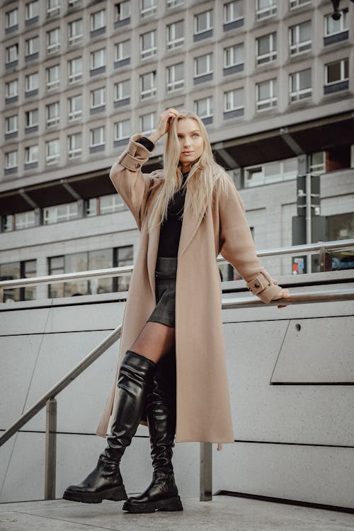 Woman in a Coat and Boots Posing by a Railing