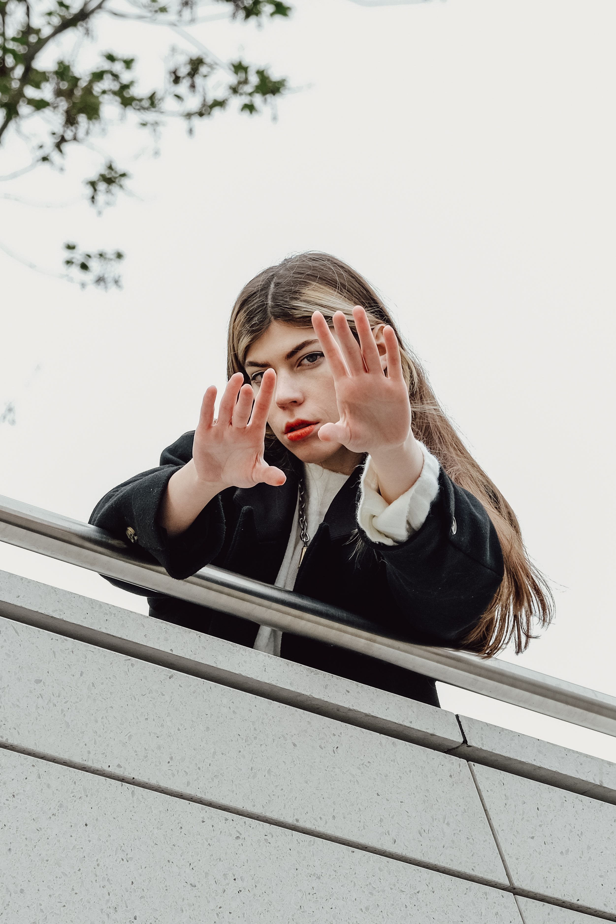Photo of a Girl Wearing a Brown Jacket Touching a Wooden Railing by a ...