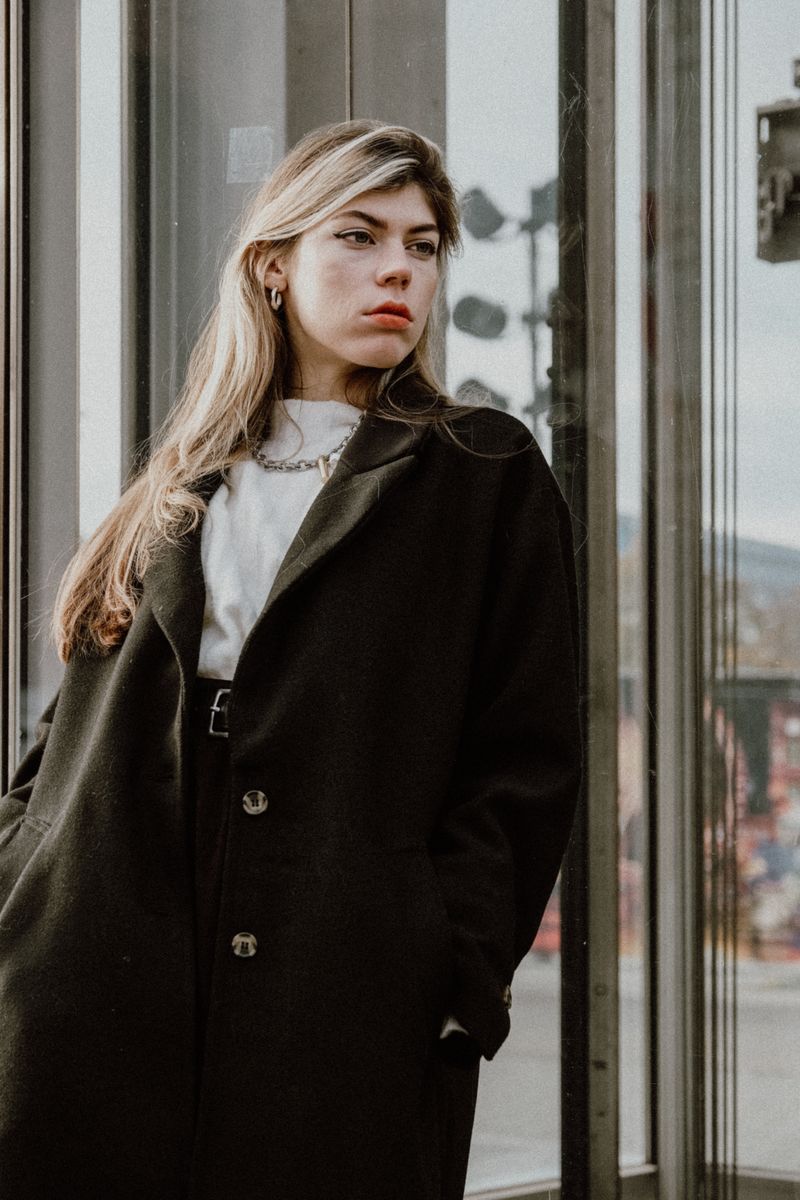 Model in a black wool coat over a white sweater in the city