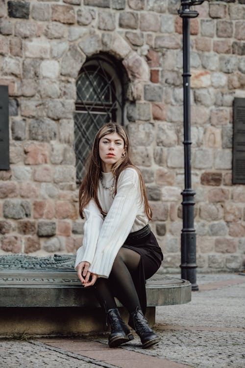 Woman in White Sweater Sitting on Plinth