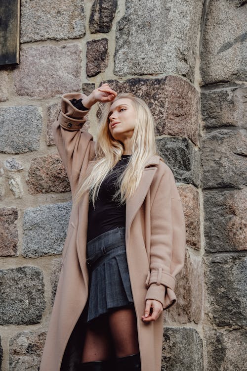 Woman posing in black pantyhose and beige trench on dark