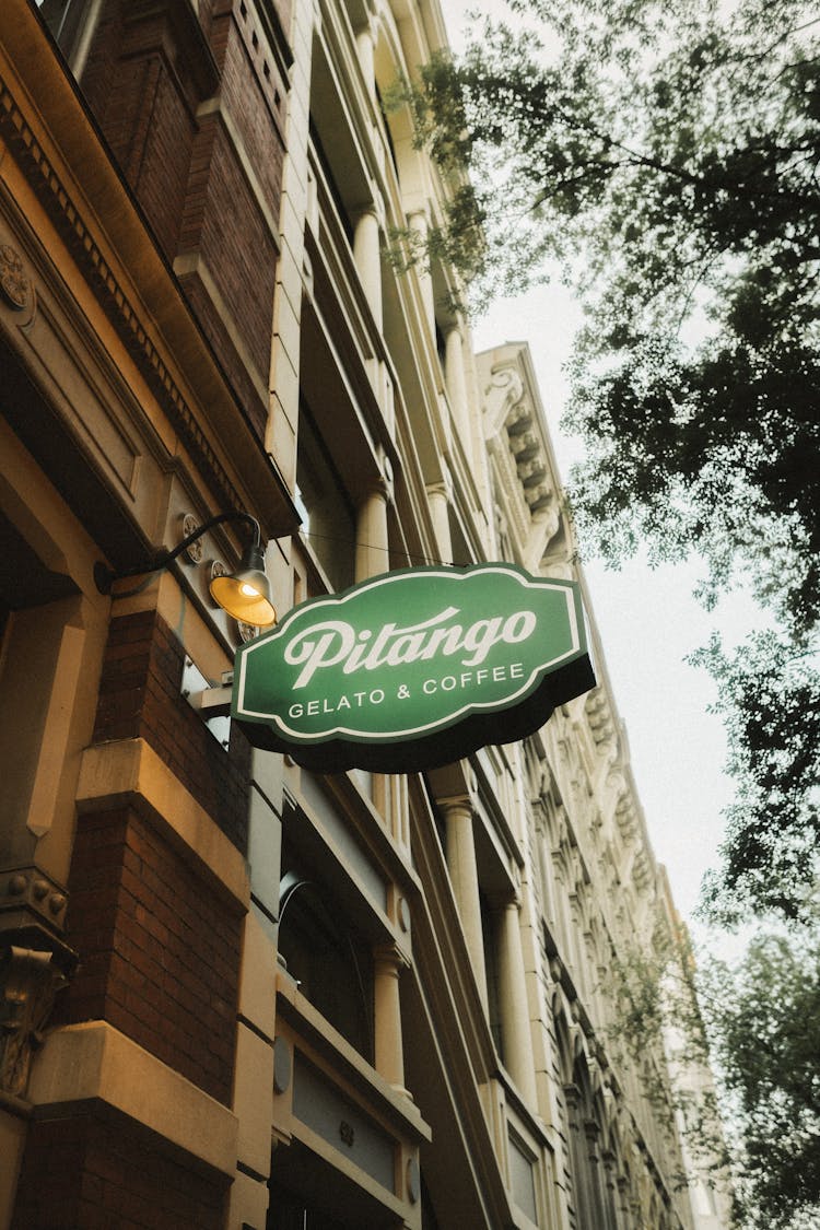 Green Cafe Sign On Wall Of Building In City