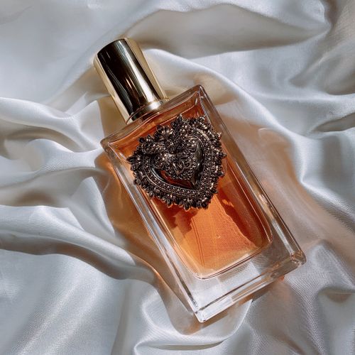 Free Elegant perfume bottle with ornate heart design on white silk fabric, exuding luxury. Stock Photo