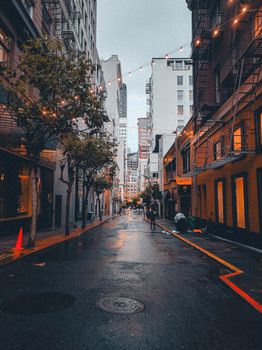 A vibrant city alley adorned with string lights and wet streets, evoking a cozy urban atmosphere.