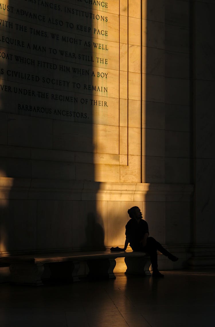 Man Sitting By Shadowed Inscription In Jefferson Memorial