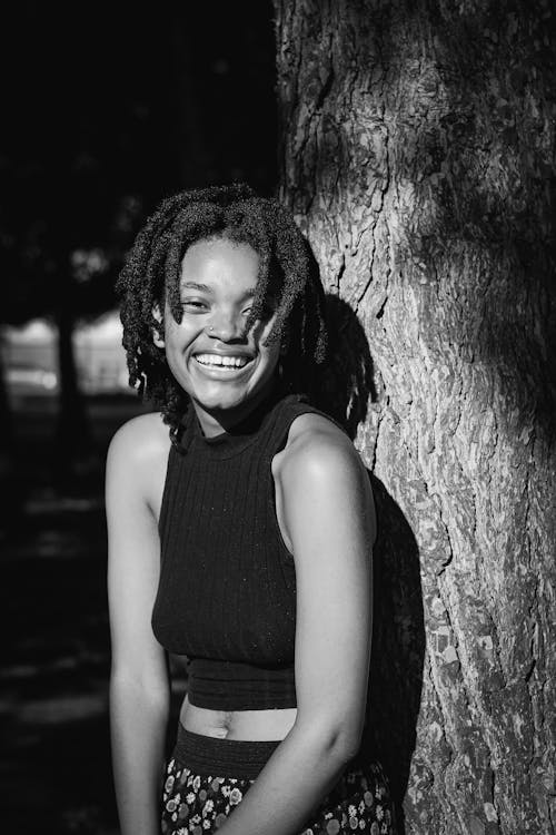 Smiling Woman Standing by Tree in Black and White