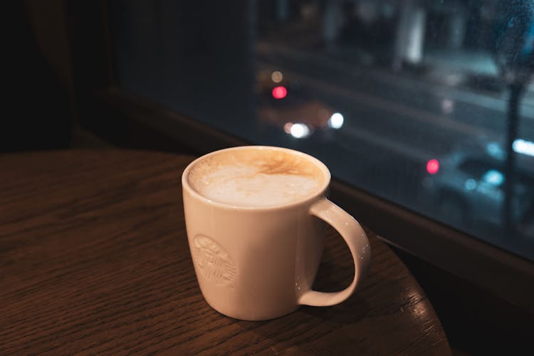 Cup Of Cappuccino With Starbucks Logo Standing On A Round Wooden Table