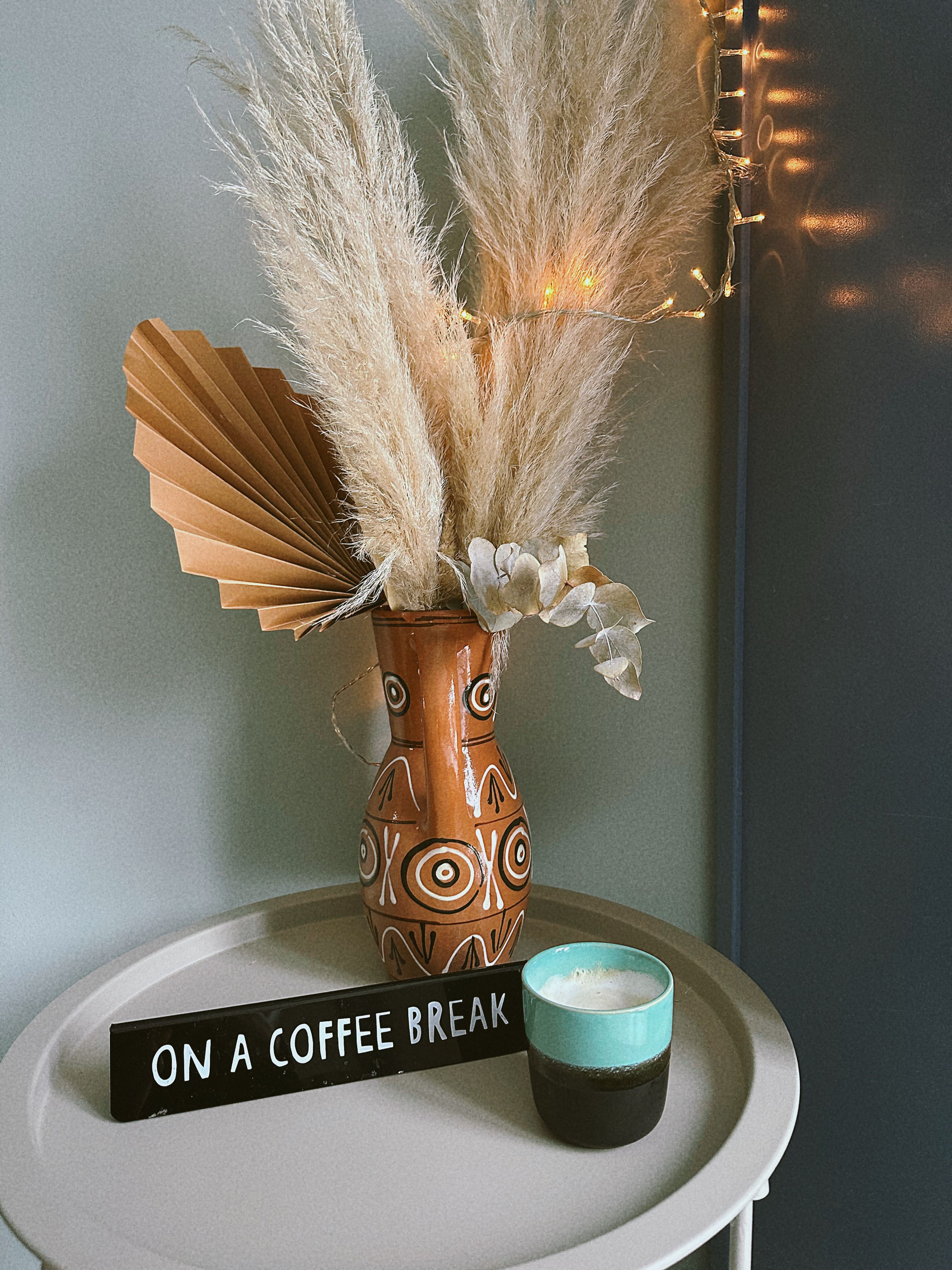 Dried pampas grass plumes arranged in a terracotta vase on a boho coffee bar shelf
