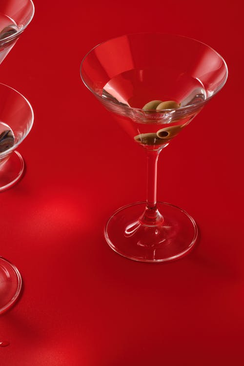 Glass of Martini with Green Olives on a Red Table