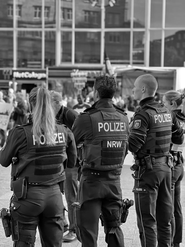 Back View Of Police Officers Standing On The Pavement In City 