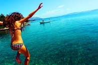 一名穿着比基尼的年轻女子跳入清澈的克罗地亚大海，享受着暑假时光